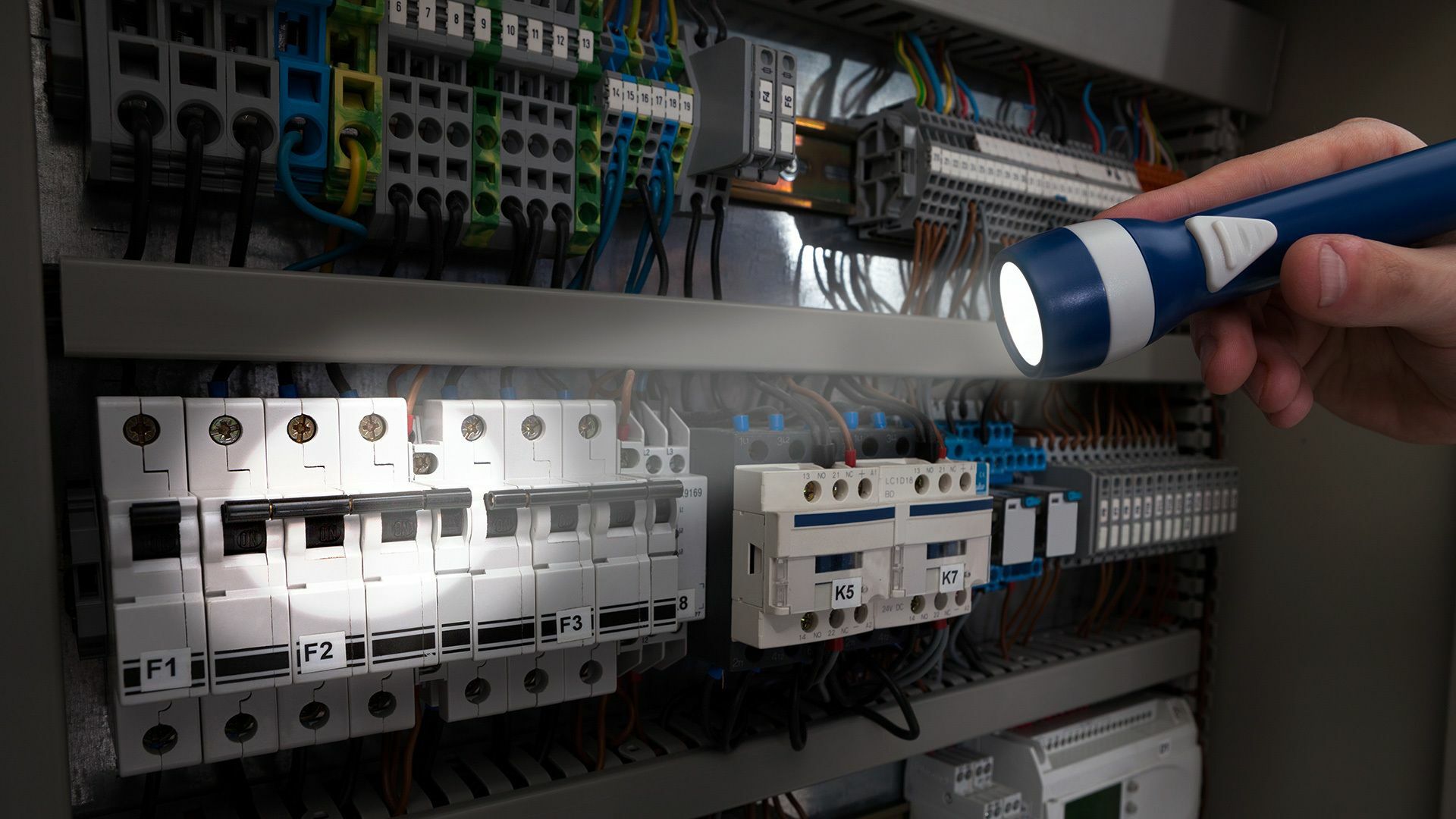 Ein Service-Techniker leuchtet mit einer Taschenlampe in einen Sicherungskasten